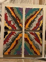 Front view showing four square canvases arranged in a 2x2 grid displaying colorful abstract wavy patterns that form a symmetrical design.