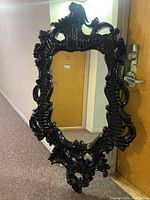 Front view of large ornate black plastic framed wall mirror showing detailed design and reflective surface.