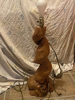 Live edge freeform maple burl lamp with twisted organic wood body shown unlit with bulb socket and power cord visible.