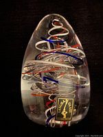 Full view of vintage Langham art glass paperweight displaying clear teardrop-shaped glass with colorful internal swirls and Langham Glass label affixed.