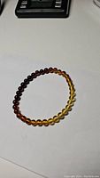 Full view of the Baltic amber bracelet showing gradient beads from dark red to yellow.