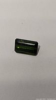 Front view of a bright green rectangular octagon cut tourmaline gemstone.