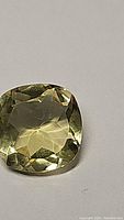 Close up front view of the deep yellow cushion cut lemon citrine gemstone showing facets and clarity.