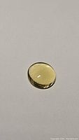 Photo of round cabochon shaped golden yellow citrine gemstone on plain background highlighting its shape, color and clarity.