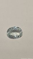 Top view of a light blue oval cut aquamarine gemstone showing clarity and facets.