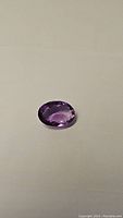 Purple amethyst oval cut gemstone approximately 13.50x9.40mm on plain background showing clarity and color