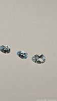 Three pear cut sky blue topaz gemstones on plain background