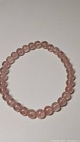 Top view of strawberry quartz bracelet showing round polished beads on stretchy band with translucent pink color and internal inclusions.