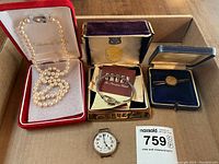 Overview of all items: pearl necklace in red box, Gruen watch and box, loose pocket watch dial and coin pin