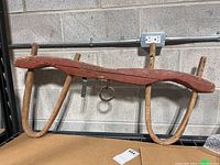 Full view of the antique yoke showing the curved wooden beam, two wooden arms, and a central metal ring for harnessing load.