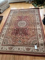 Overall view of the medium sized area rug showing full pattern, colors, and condition including discoloration.