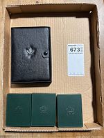 The entire lot consisting of one black leather case with an embossed maple leaf and three green coin cases.