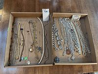 Top-down image showing a variety of necklaces, chains, and a pearl bead necklace arranged in two cardboard trays.
