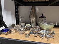 Full shelf view showing a variety of silver-plated items and glass bowls
