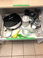Drawer containing all items: George Foreman grill, Osterizer blender parts, two handheld juicers, milk frother, cheese grater, glass bowls.