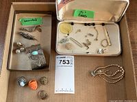 Overview of jewelry items including rings, pearl necklace, cuff bracelet, pins, and various small pieces organized in boxes.