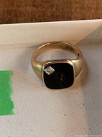 Front view of ring showing black onyx inlay, diamond accent, and gold band.