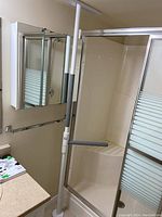 Tension bar installed vertically in bathroom between floor and ceiling, near shower with sliding glass doors and wall-mounted mirrored cabinet.