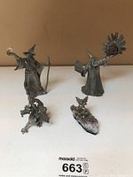 Four pewter figurines displayed including two wizards, a dragon, and an angel on geode base.