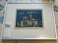 Overall view of the framed woodcut print with silver metal frame, white mat, depicting cathedral scene