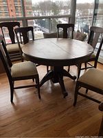 Round table set up with six chairs around, by window