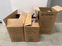 Three cardboard boxes on the floor. Boxes are signed as containing Stihl and Husqvarna chainsaw parts, marked new.