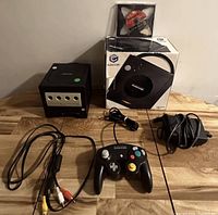 Photo of Nintendo GameCube bundle components including console, controller, cables, power adapter, game disc, and original box