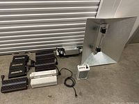 Overview of the grow light ballasts, reflector hood, and controller laid out on the floor.