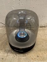 Harman Kardon SoundSticks Wireless Speaker powers on, showing blue LED light ring inside transparent dome, from front view.