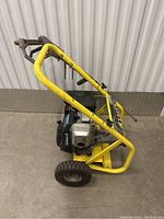 Side view of pressure washer showing yellow steel frame, engine, wheels
