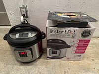 Instant Pot with lid closed next to its original retail box showing product branding and features.