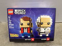 Front view of sealed LEGO BrickHeadz set 41611 box showing Marty McFly and Doc Brown figures on blue lightning background with Back to the Future logo, piece count and age rating.