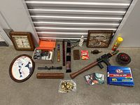 Photo showing entire lot with toy gun, framed artwork, flutes, buttons, Scrabble Slam, CD albums, and household items arranged on the floor.