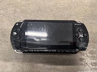 Front view of black Sony PSP console with directional pad, screen, and controls.