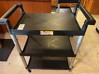 Front view of the black and silver Maxworks 3-shelf utility trolley with its 3 stacked shelves.