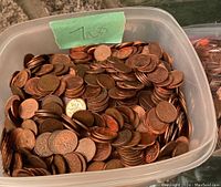 Plastic container filled with mixed pennies with a green paper label marked '7 LBS'.