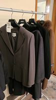 Five women’s coats on hangers, front view