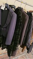 Multiple coats and jackets hanging on a rack showing all lot items