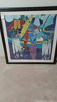 Full view of framed abstract art piece showing colorful geometric design with stylized fish