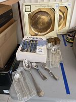 Overview of charger plates, napkin rings, flatware in package and unpackaged flatware on a table.