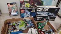 Wide shot of cardboard box filled with loose LEGO pieces and some boxed sets in the background