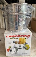 New in box Lagostina Veneto 6.2L multi-purpose pasta cooker set stacked on top of box, partially covered in plastic wrapping.