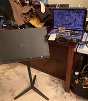 Adjustable Wenger black metal music stand set up next to oboe case