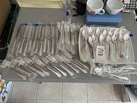 Overview of Oneida Community silver plated knives, forks, spoons, and Mikasa platter on table.