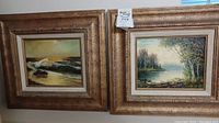 Pair of two framed original paintings. Left one depicts ocean waves hitting shore with rocks and a cloudy sky. Right one depicts a calm lake or river scene with trees on the bank and light sky background.