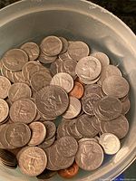 Image showing multiple US coins in a plastic container including quarters, pennies, nickels, and dimes