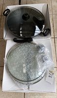 Wok set arranged in white box, one lid on wok, two additional lids wrapped in bubble wrap below