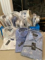 Blue shipping box filled with multiple packaged men's dress shirts, with some shirts displayed in front