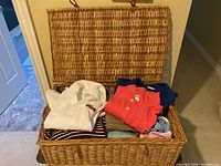 Wicker basket open showing folded knit tops including Lacoste and other brands