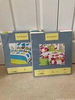 Two Four Seasons bed sheet sets in original packaging with colorful patterns shown.